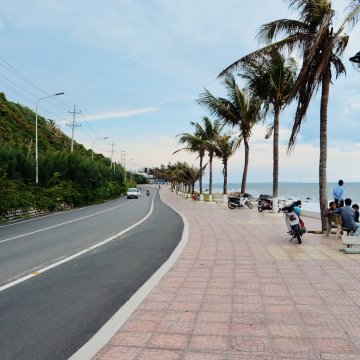 a road with a bit of a turn in it beside an ocean